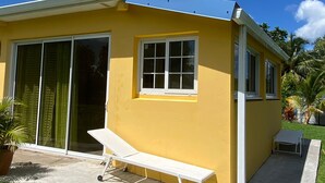 A yellow building with large sliding glass doors, a small window, and a white bench outside.