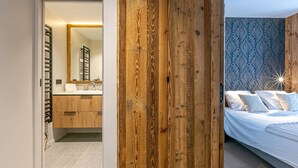 Une chambre à coucher moderne avec une tête de lit en bois, un grand lit avec une literie blanche et un mur orné d’un motif bleu.