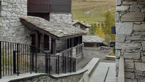 Un bâtiment en pierre doté d’un balcon en bois et offrant une vue sur une vallée.
