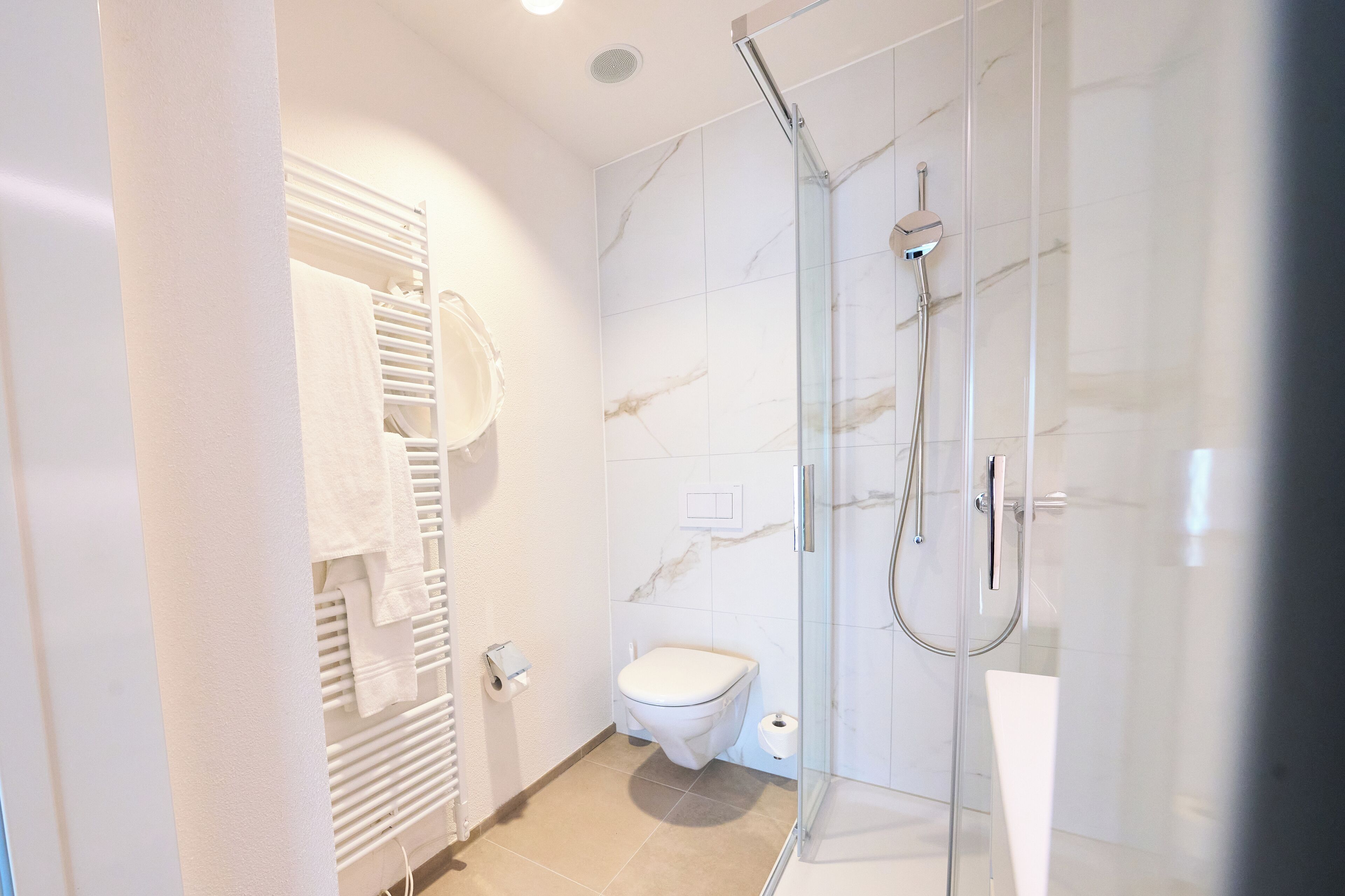 Ein modernes Badezimmer mit einer Duschkabine, einer Toilette und einem Handtuchhalter.