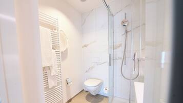 Ein modernes Badezimmer mit einer Duschkabine, einer Toilette und einem Handtuchhalter.