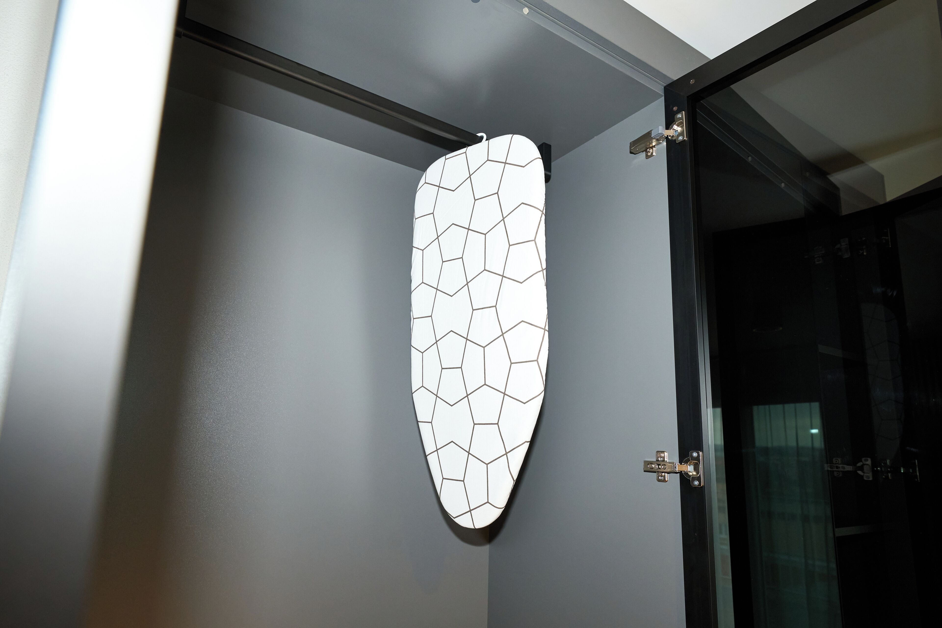 A wall-mounted geometric-patterned object, possibly a decorative panel or artwork, in a room with a modern design.