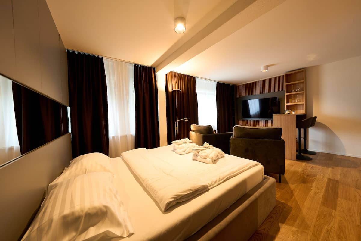 Een hotelkamer met een groot bed, een bureau, een stoel, een televisie en een houten vloer.