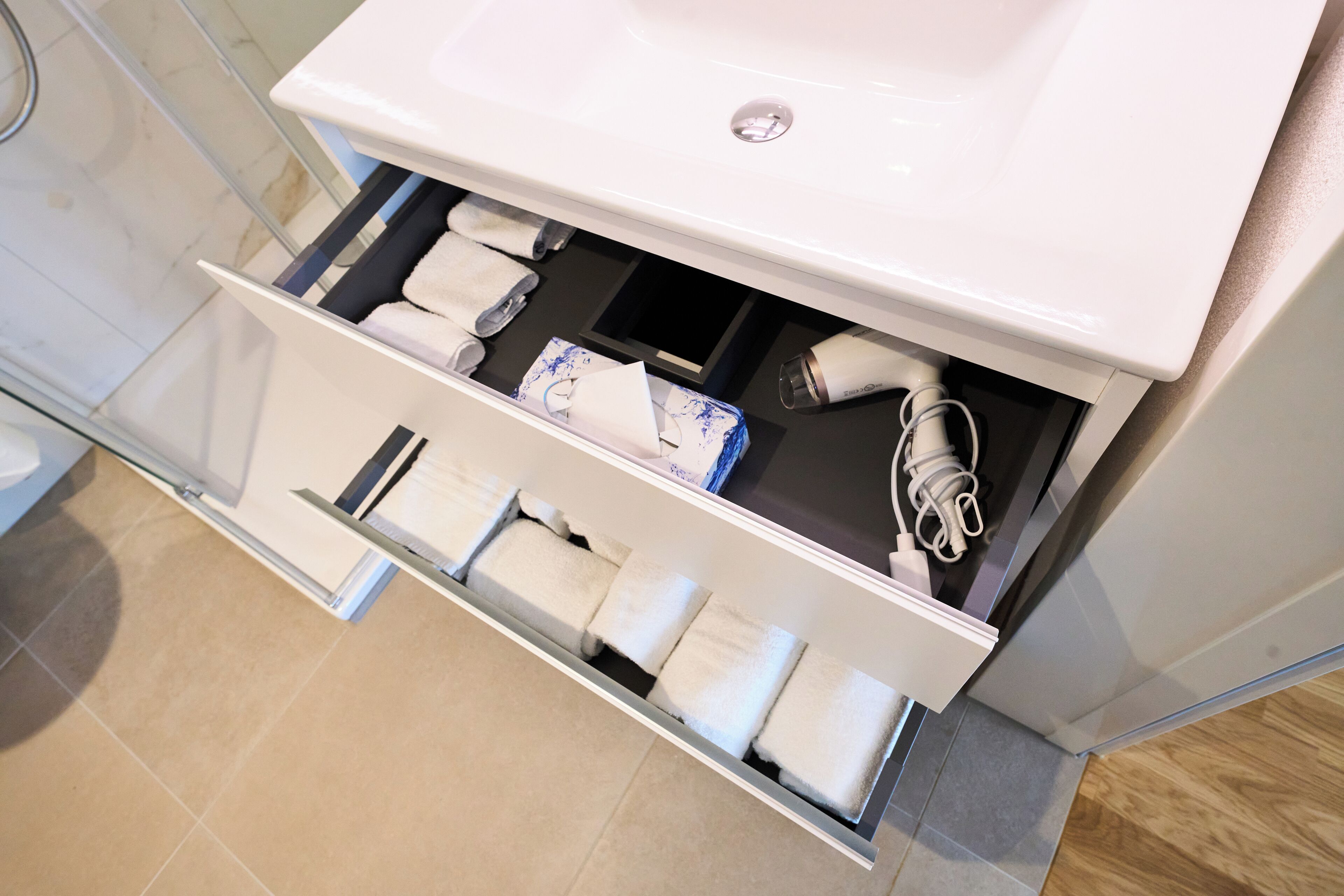 Un baño con lavamanos blanco, toallero y dispensador de toallas.