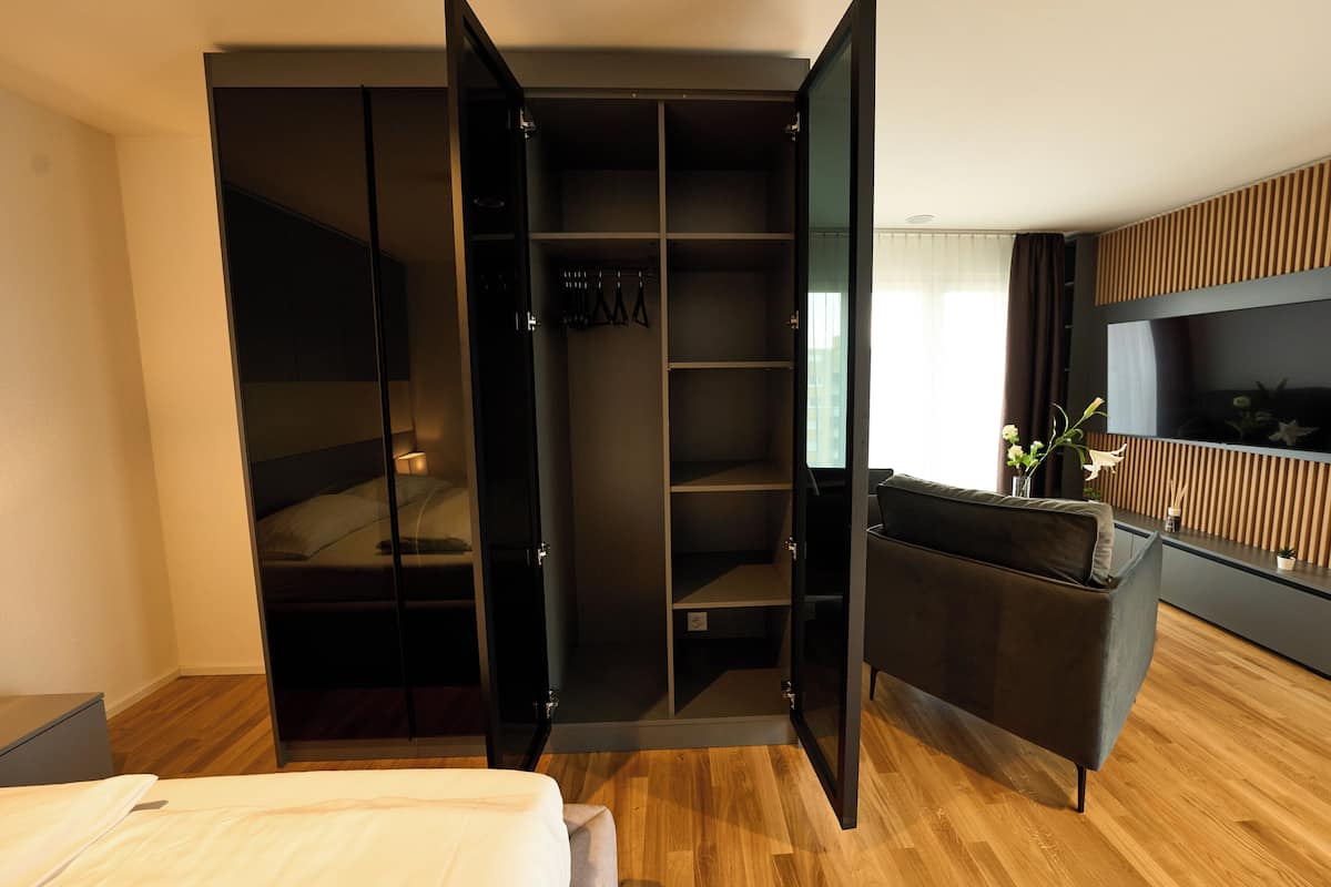 Een moderne slaapkamer met een inbouwkast, een nachtkastje en een grote spiegel.