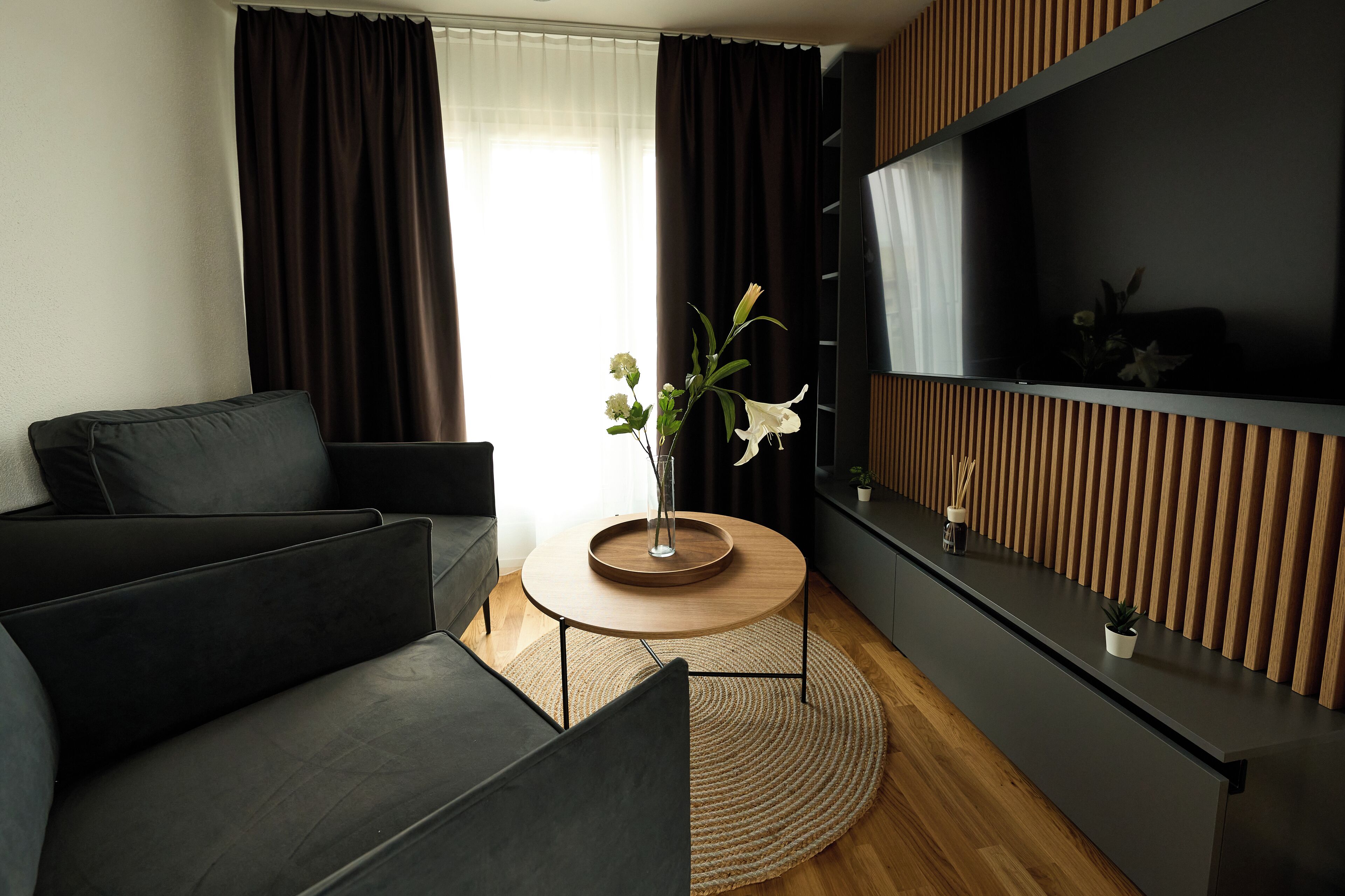 A modern living room with a sofa, a coffee table, and a TV on a wooden wall.