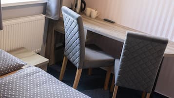 A room with two beds, a desk, and a chair.