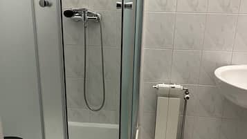 Un baño con ducha de vidrio, lavabo blanco y retrete.