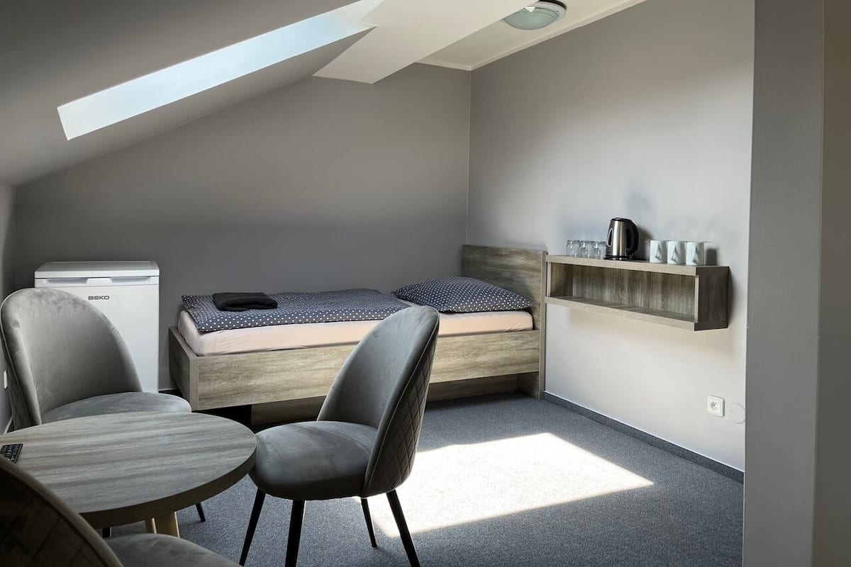 Une pièce de taille modeste comprenant un lit en mezzanine, un bureau et une chaise.