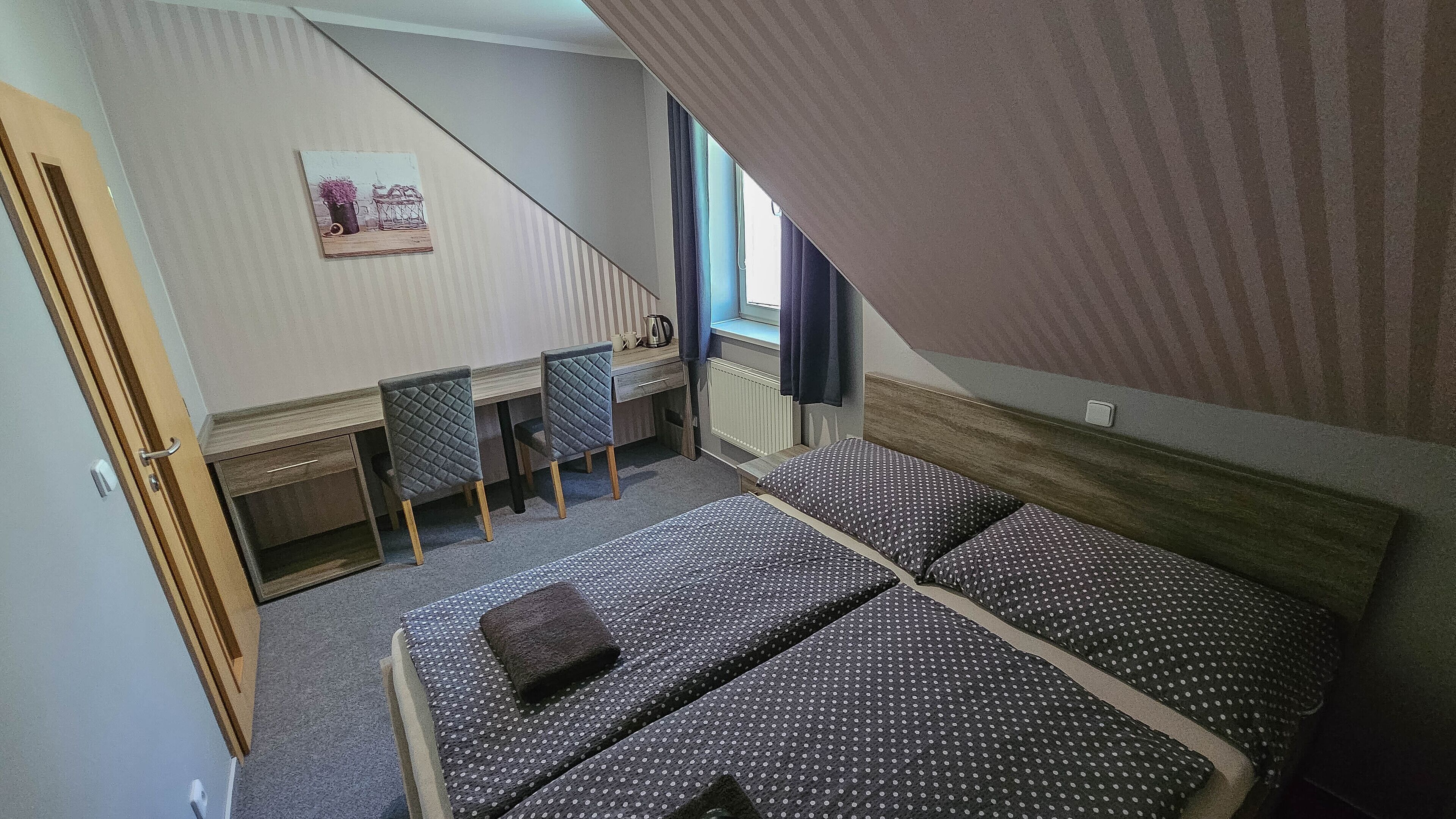 A bedroom with two beds, a desk, and a chair.