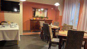 Un comedor con una mesa preparada para cuatro personas, un aparador de madera con espejo y sillas de mimbre.