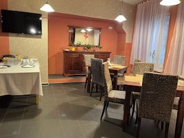 Uma área de refeições com uma mesa posta para quatro pessoas, um aparador de madeira com espelho e cadeiras de vime.