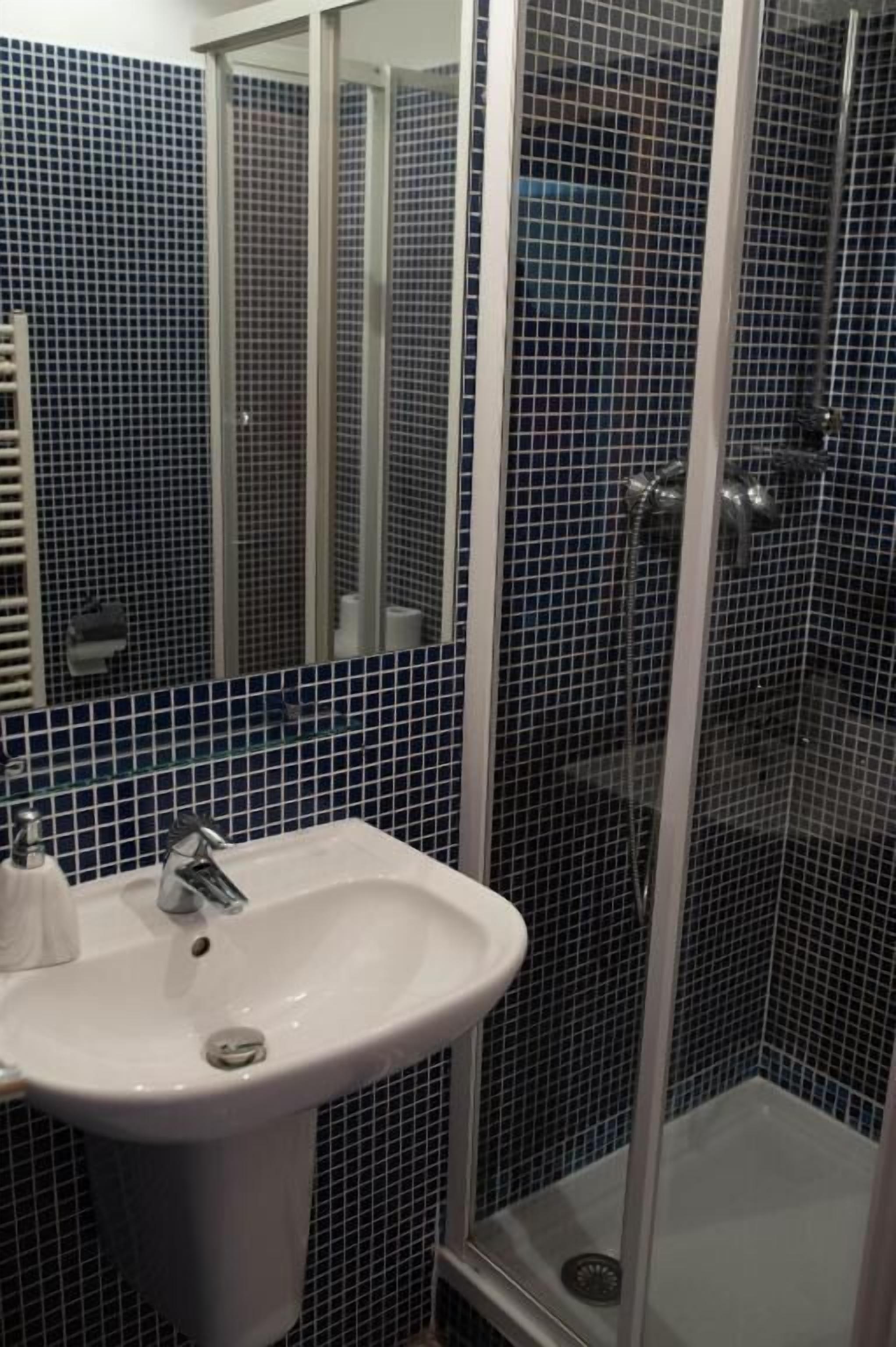Ein Badezimmer mit einem weißen Waschbecken, einem Spiegel und einer Duschkabine.