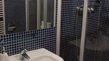Ein Badezimmer mit einem weißen Waschbecken, einem Spiegel und einer Duschkabine.