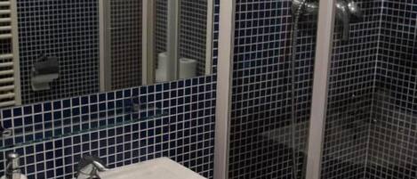 A bathroom with a white sink, a mirror, and a glass-enclosed shower.