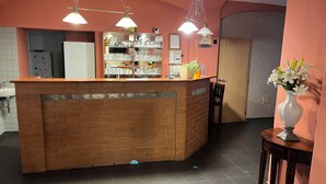Zona de recepción con un mostrador de ladrillo, estanterías con cristalería y un jarrón con flores.