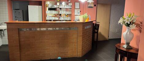 A reception area with a brick counter, shelves with glassware, and a vase with flowers.