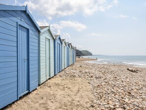 A row of beach huts along a pebbly beach with the sea in the background. - Hook Farm Cottage (Lyme Regis)