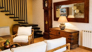A room with a staircase, a wooden cabinet, a clock, and a lamp.