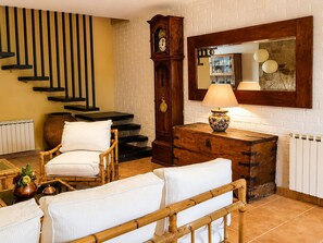 Una habitación con una escalera, un armario de madera, un reloj y una lámpara.