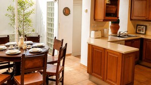 A kitchen with wooden cabinets, a dining table set for four, and a view of the outdoors through a glass door.