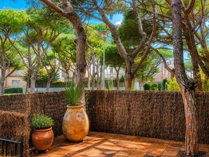An outdoor patio area with a tiled floor, a woven wall, and potted plants. - Stunning Villa in Platja d'Aro: 100m from Beach, Terrace, A/C, Family-Friendly (Platja d'Aro)