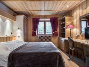 Ein Zimmer mit Holzboden, einem Bett, einem Schreibtisch und einem Stuhl.