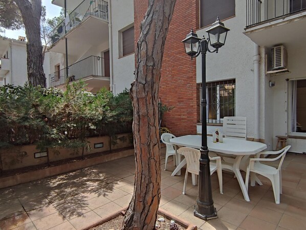 An outdoor patio area with a table and chairs, a lamp post, and a tree.