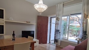 A dining area with a wooden table and chairs, a television, and a chandelier. - Cozy Apartment with Terrace Near Beach and Shops in Costa Brava (Platja d'Aro)