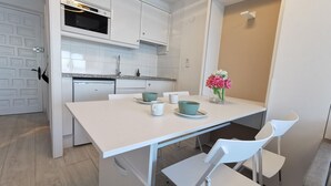 A modern kitchen with white cabinetry, a built-in oven, and a dining area with a white table and chairs. - Renovated beachfront studio with parking in Platja d'Aro (Platja d'Aro)