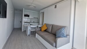 A compact living space with a kitchenette, a sofa with cushions, and a dining area. - Renovated beachfront studio with parking in Platja d'Aro (Platja d'Aro)