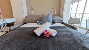 A neatly made bed with a dark gray duvet, two pillows, and a bouquet of pink flowers. - Renovated beachfront studio with parking in Platja d'Aro (Platja d'Aro)