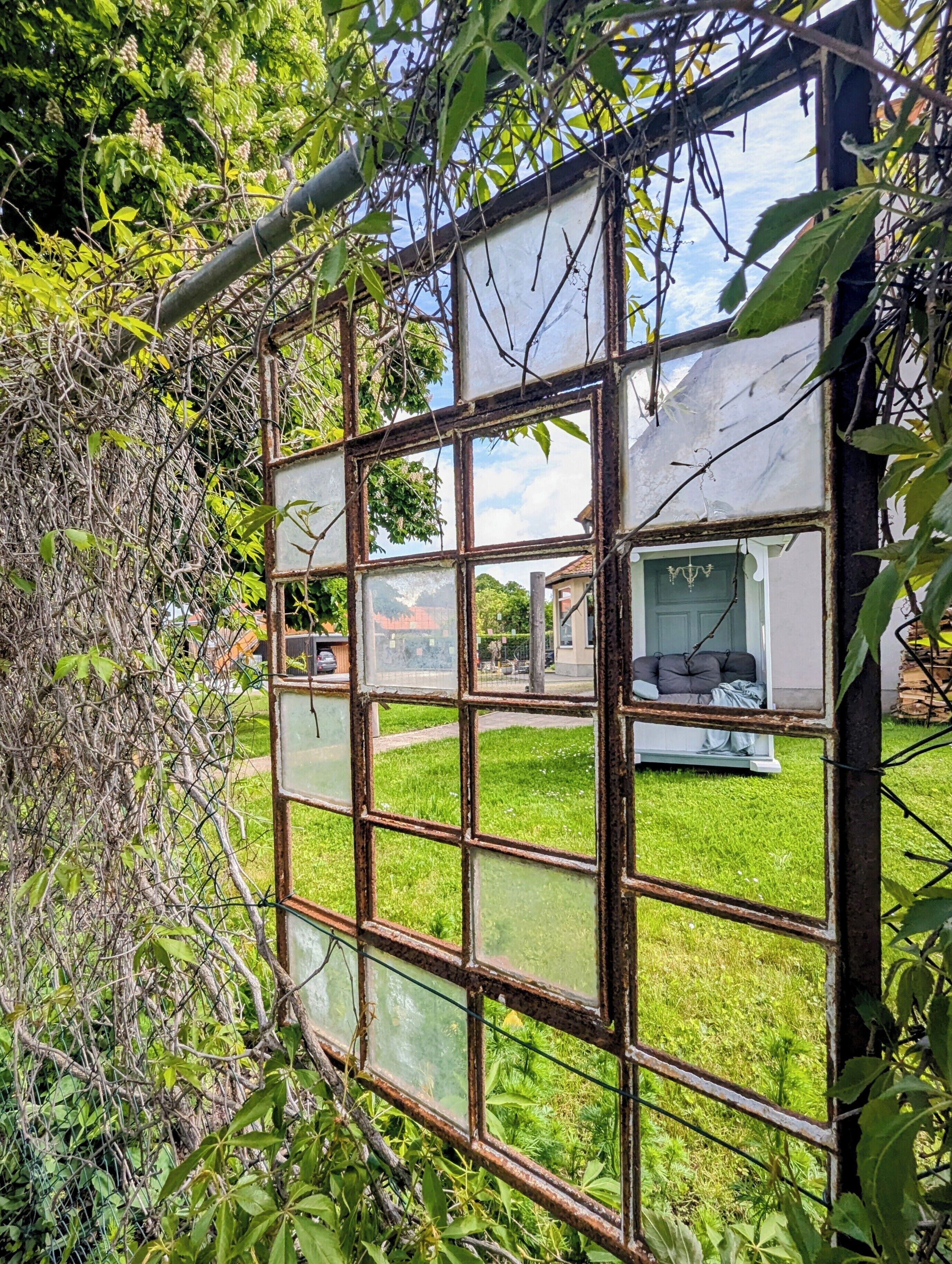 A window with a view of a grassy area and a building in the background.