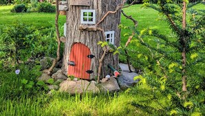 Una casetta sull'albero con tetto rosso, diverse finestre e un camino.