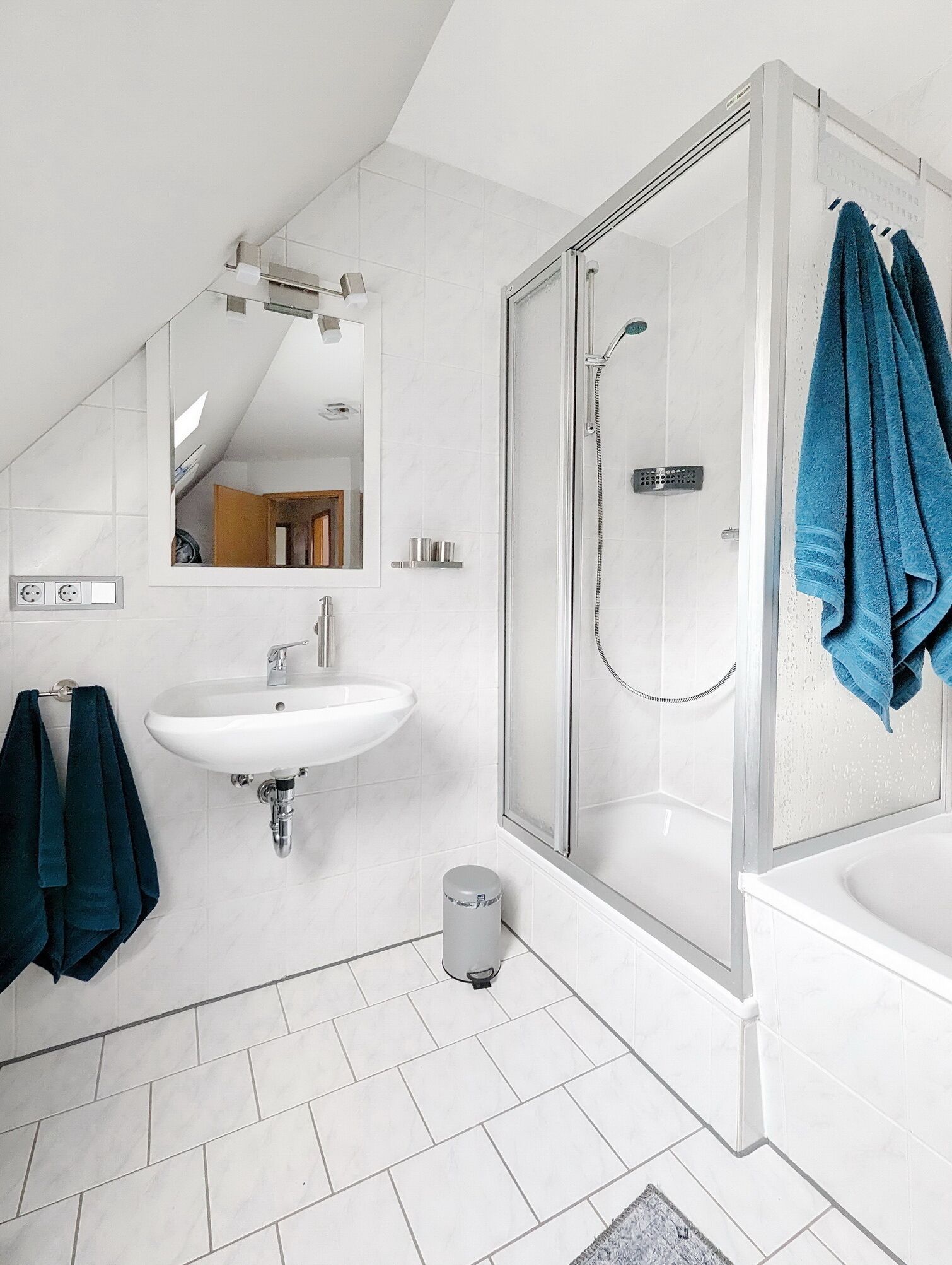 A modern bathroom with a white sink, mirror, and shower.