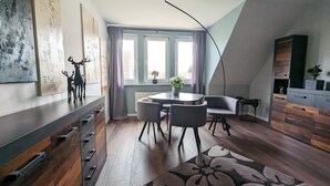 Un moderno loft con zona pranzo, divano, un'ampia finestra con tende e una scala.