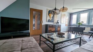 Un soggiorno moderno con una TV a schermo piatto, un tavolino in vetro e un divano.