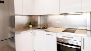 Uma cozinha moderna com eletrodomésticos de aço inoxidável, armários brancos e forno embutido.