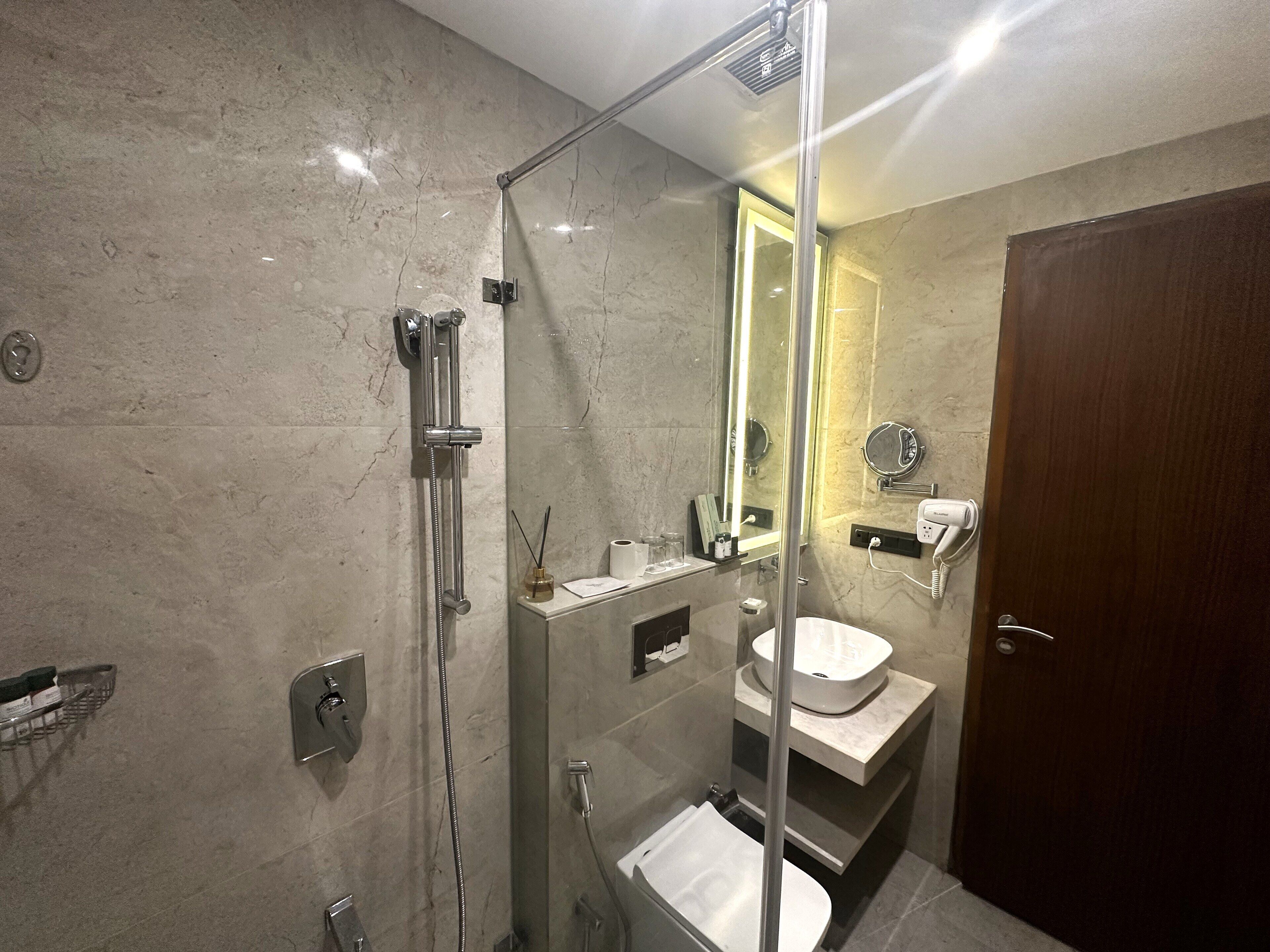 Een moderne badkamer met een douchecabine van glas, een wastafel en een toilet.