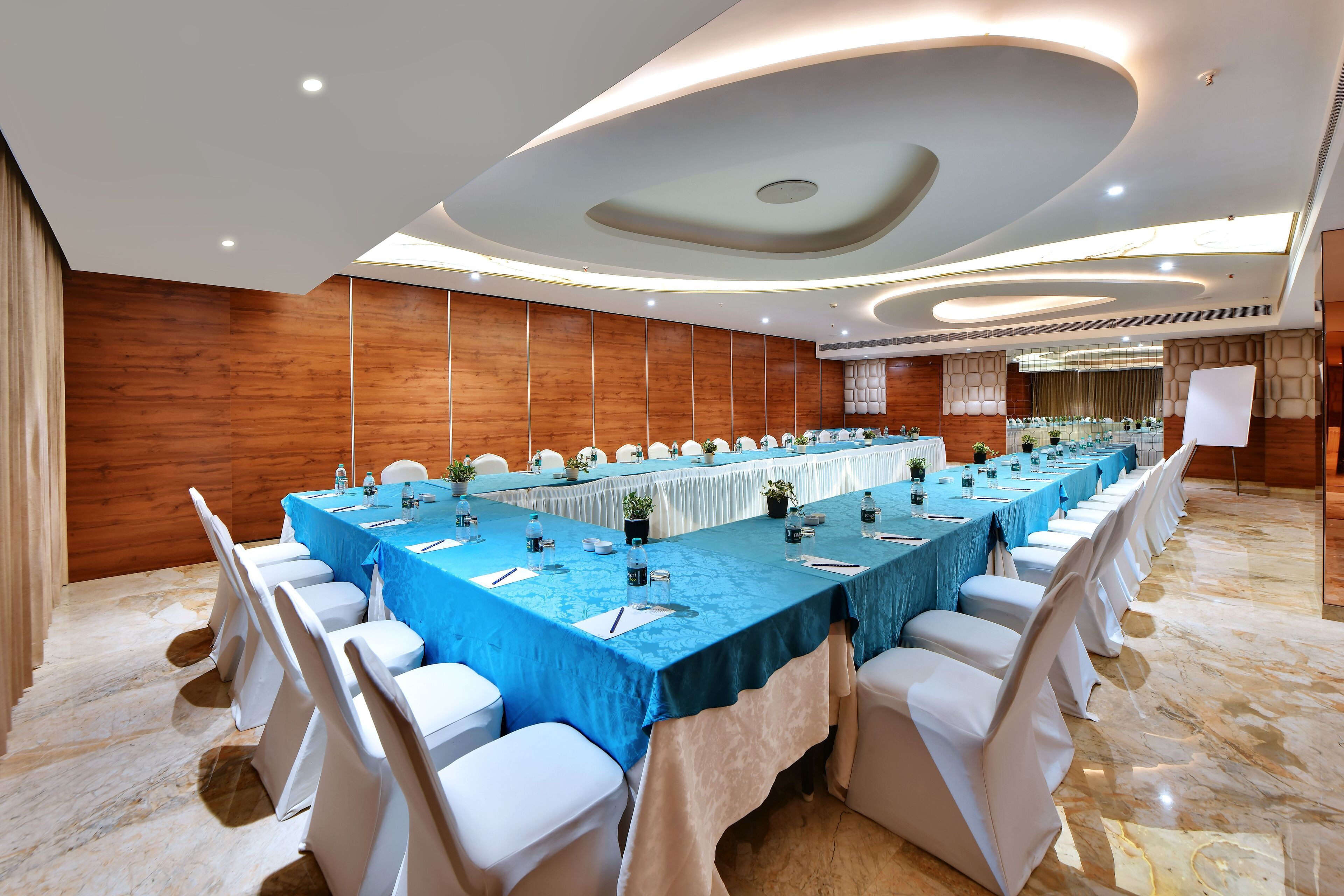 A conference room with a long table, white chairs, and a blue tablecloth.