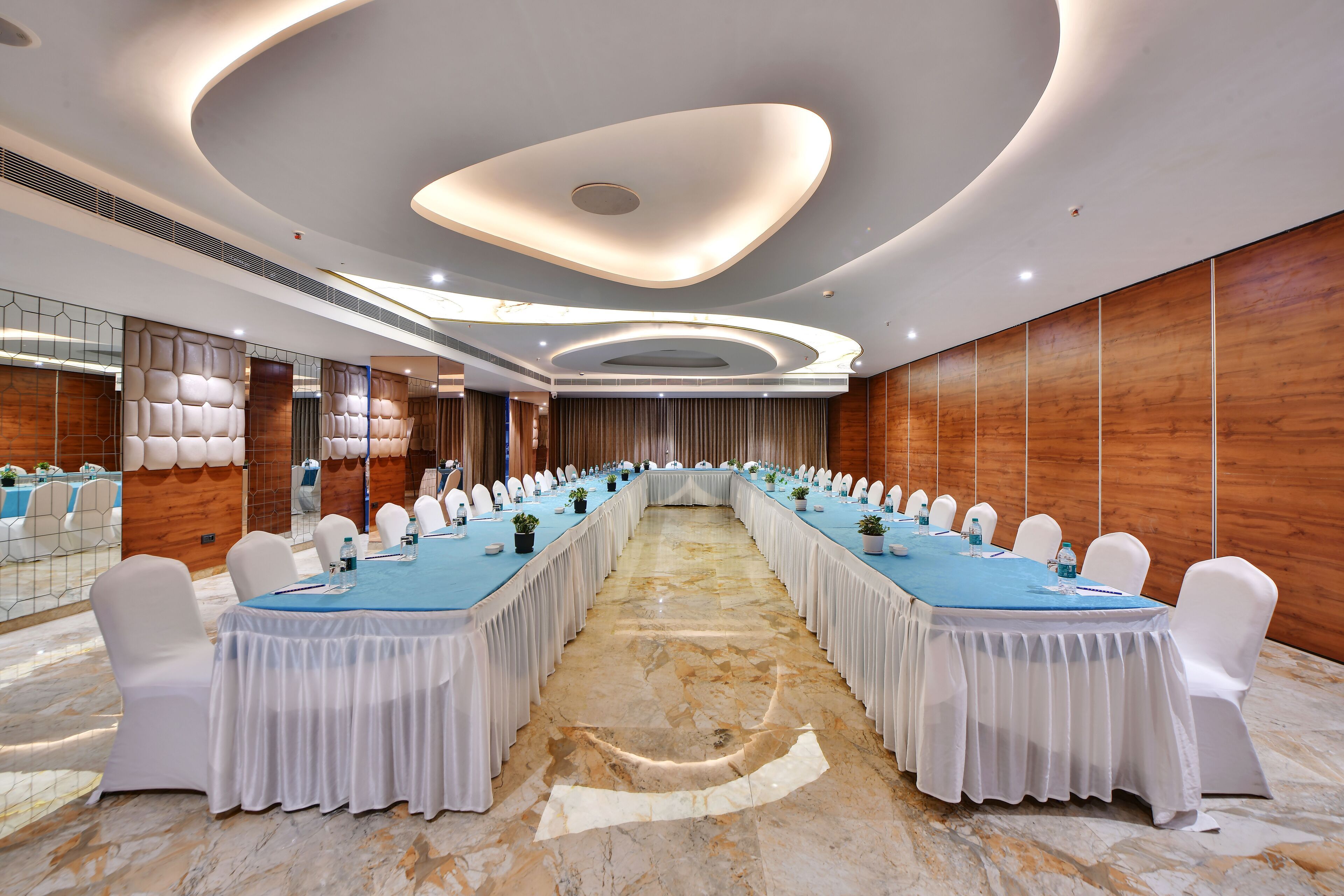 Un salón de conferencias con una larga mesa, sillas blancas y piso de mármol.