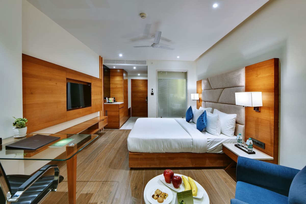 A modern hotel room with a bed, desk, chair, and a TV.