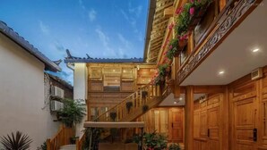 A traditional wooden building with a staircase, potted plants, and a bench. - yunchengyijing (Lijiang)
