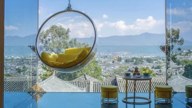 A hanging chair with a view of a cityscape and mountains. - yunchengyijing (Lijiang)