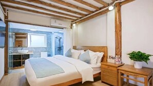 A bedroom with a wooden bed, bedside table, and a small bedside plant. - yunchengyijing (Lijiang)