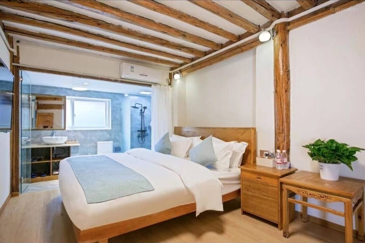 A bedroom with a wooden bed, bedside table, and a small bedside plant.