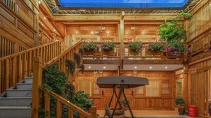 A wooden interior with a staircase, a swing chair, and hanging flower baskets. - yunchengyijing (Lijiang)