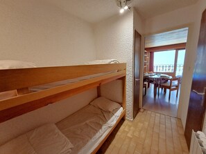 Una habitación con literas, un balcón con mesa y sillas, y vistas al exterior.