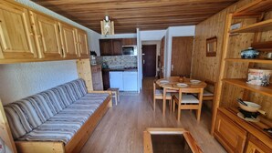 Ein kompakter Wohnbereich mit Sofa, Esstisch und Küchenzeile.
