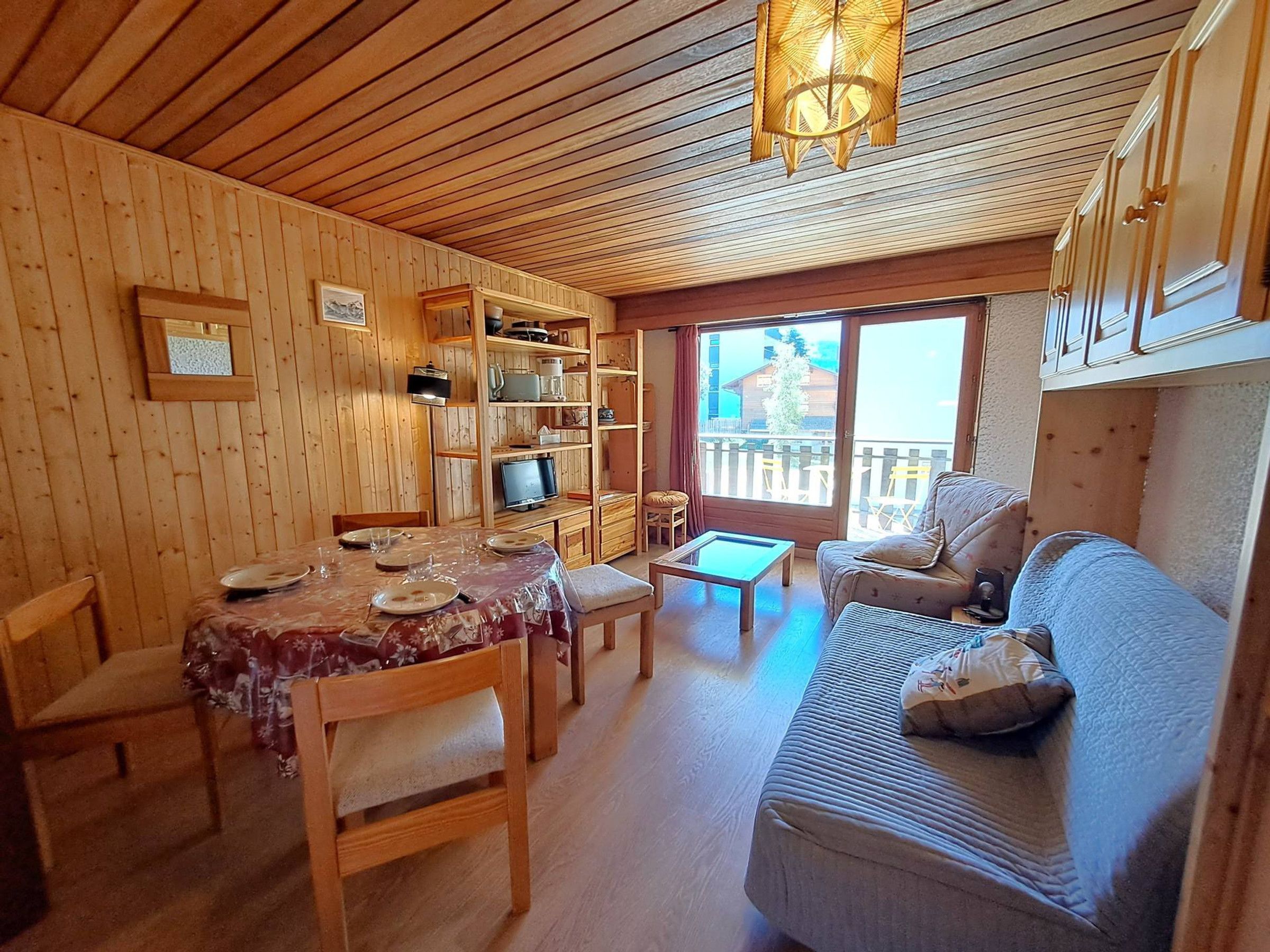Un intérieur en bois comprenant une table à manger, des chaises, un canapé et un téléviseur.